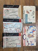 Photo showing five vintage textile pattern booklets and sheets arranged on a wooden surface