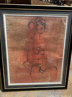 Full view of the vintage framed print showing the female figure on an orange background, mounted in a dark frame with thin metallic trim.