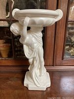 Front angle view showing cherub figure holding the planter bowl above the base.