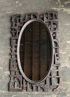 Full view of the vintage oval mirror showing the complete resin frame with Brutalist style geometric and textured details.