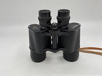 Front view showing the binoculars standing upright with eyepieces facing forward, exhibiting textured black coating and central focus wheel.