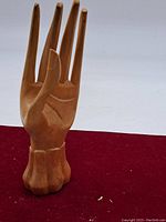 Carved wooden hand sculpture showing front view with palm and fingers extended.
