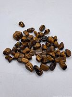 Pile of polished tiger's eye stones showing their golden-brown hues and smooth surfaces.