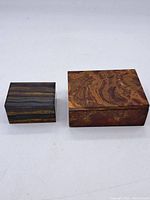 Photo showing both stone trinket boxes side by side, highlighting their size difference and distinct patterns.