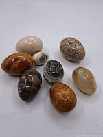Lot showing all 8 polished eggs arranged on white background with various patterns and colors.