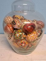 Front view of clear glass vase filled with ornately painted eggs