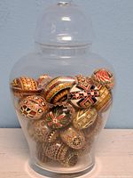 Lidded glass ginger-jar style vase filled with painted eggs