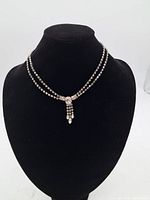 Full view of the vintage Coro necklace displayed on a black velvet bust, showing double strands of clear rhinestones with a centered dangling pendant detail.