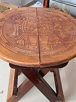 Close-up of the round carved leather seat with Aztec-style design and visible wear.