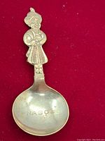 Front of the vintage Nabob spoon showing the figurine handle of a person wearing traditional attire and the stamped NABOB on the bowl
