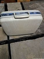 Side view of vintage white Samsonite suitcase showing textured surface and chrome locking mechanisms.