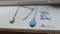 Photo showing both necklaces side by side with the cameo pendant and blue stone pendant visible along with the 925 Jewelry label.