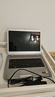 Front open view of Sony Vaio laptop showing keyboard, screen, and part of power cord on a white surface.