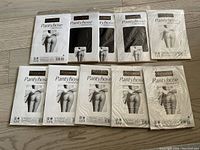 10 packages of ladies black nylon pantyhose arranged on floor, new and sealed in box.
