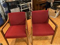 Two armchairs with oak wood frames and red fabric upholstery positioned side by side showing overall condition and style.