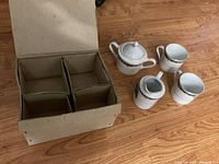 Four china pieces packed in a cardboard box with four compartments, packed for shipping or storage.