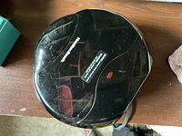 Closed view of black Hamilton Beach electric grill showing curved rectangular shape with logo and indicator light.