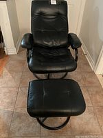 Front view of black leather recliner chair and matching ottoman showing padded tufted seat and back with tubular steel frame.