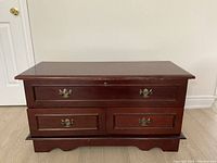Front view of solid wood bedroom storage bench with three drawers and top lid closed.