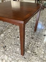 Close-up of mahogany table corner showing wood grain, beveled edge, and tapered leg with groove detailing.