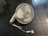 Top view photo of white wall mount oscillating fan with three blades and white power cord