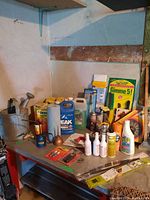 Overview of the automotive fluids and garden food on a workbench, including antifreeze, vegetable garden food, sprays, and brass valve