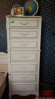 Full front view of seven-drawer tallboy dresser with globe and radio on top