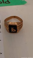 Front image of 10K gold men's ring showing black onyx stone with gold letter 'L'.