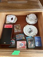 Top view of drawer showing playing cards, decorative rock, cup, saucer, and ashtray.