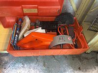 Orange plastic case containing a Black and Decker work wheel power stripper and sander along with brushes, sanding pads, and cables.