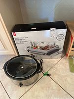 Buffet server and warming tray box with Rival crock pot in front on floor.