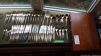 Full view of all flatware pieces displayed on a green surface alongside closed wooden case.