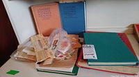 Overview of the lot showing two hardcover stamp catalogues, several albums, and loose stamps packed in plastic bags and envelopes.