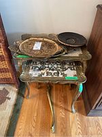 Photo showing stacked large and smaller decorative side tables with four metal trays on top. Hardwood floor visible.
