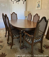 Wood dining table set with six chairs around an oval wood table in dining room.