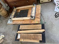 Wooden dolly upside down showing 4 caster wheels and surrounding wood planks and strips.