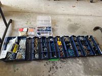 Wide photo of large roll-up case fully opened showing compartments filled with assorted screws, bolts, washers, and anchors with smaller plastic cases and packs on top.