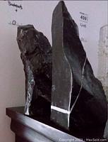 Photo of two large dark mineral stone bookends with white veining, positioned upright on a wooden surface.