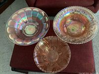 Top view of the three vintage iridescent dishes: 12 inch shallow dish with scalloped pattern, 11 inch dish on three feet, 8.5 inch dish with floral pattern
