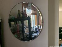 Round wall mirror measuring approximately 24 inches in diameter, showing wear on the glass surface.