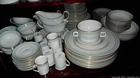 Overview of Royal Doulton Berkshire dinnerware including stacks of plates, bowls, cups, saucers, sugar, creamer, and gravy boat