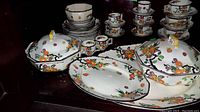 Two covered serving bowls with lids at front, oval platter behind