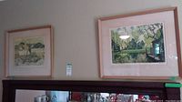 Two framed prints hanging above a fireplace mantle, showing landscape artwork.