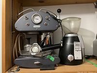 DeLonghi espresso machine and Starbucks coffee grinder on wooden shelf
