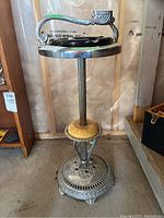 Full view of vintage metal floor stand ashtray showing ornate chrome design with yellow painted accent and sand-filled ashtray top with handle.
