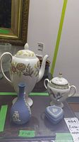 Overall photo showing all items in the lot: porcelain coffee pot with floral design, sugar bowl with lid and bird motif, blue jasperware bud vase, and heart-shaped trinket box.