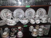 Overall view of cabinet shelf showing full set of plates, cups, saucers and serving pieces