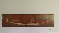 Full horizontal view of carved wood wall art featuring a long, abstract figure with turquoise highlights on a brown wood panel.