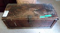 Front view of old wood chest showing paint stains and metal latch