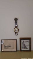 Overall view of two framed nautical artworks and the wall barometer above.